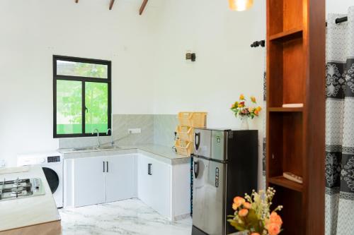 a kitchen with white cabinets and a refrigerator at JY Apartments in Negombo
