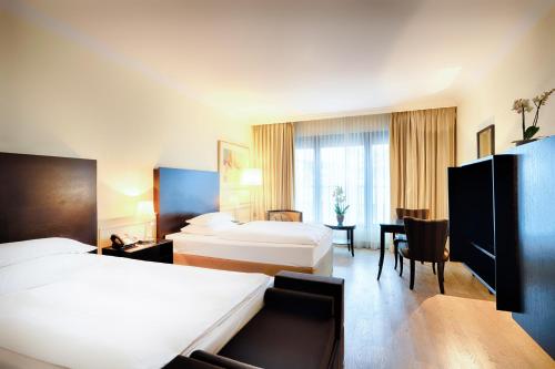 a hotel room with two beds and a table at Welcome Parkhotel Euskirchen in Euskirchen