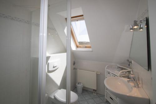 a white bathroom with a sink and a toilet at Ferienwohnung Filter in Hörnum