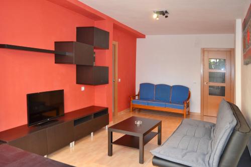 a living room with red walls and blue chairs and a television at Apartamento Goya in Málaga
