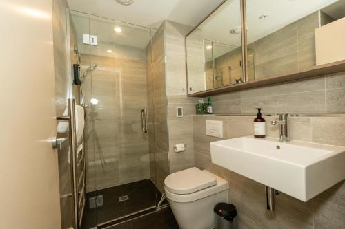 a bathroom with a sink and a toilet and a shower at Hygge Garden Apartment with Private Sauna in Queenstown