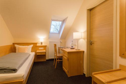 Kleines Zimmer mit einem Bett, einem Schreibtisch und einem Bett. in der Unterkunft Landhotel Grätz in Emmering