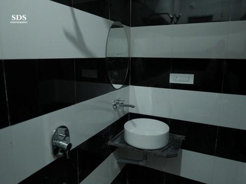 a black and white bathroom with a sink and a mirror at Hotel Chandra Hari Palace in Sānchor