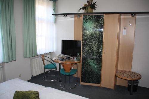 a hotel room with a table and a desk with a computer at City-Hotel in Plauen