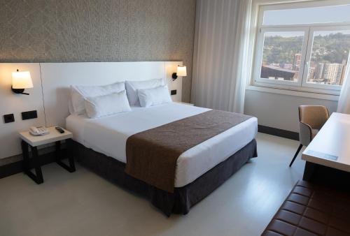a hotel room with a large bed and a window at Hotel Ilunion Bilbao in Bilbao
