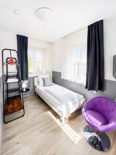 a bedroom with a bed and a purple chair at FlyInn-Pension Airport-Messe in Leinfelden-Echterdingen