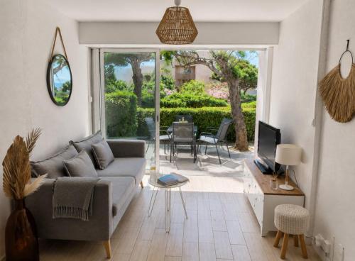 a living room with a couch and a television and a patio at Le Cosy - T4 avec terrasse privée, Face à la mer avec parking et wifi in Sète