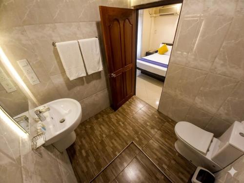a bathroom with a sink and a toilet and a bed at Hotel Lakefield in Kandy