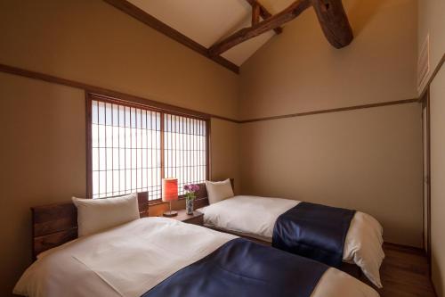 two beds in a room with a window at Hikoso-machi Gin no Ma in Kanazawa