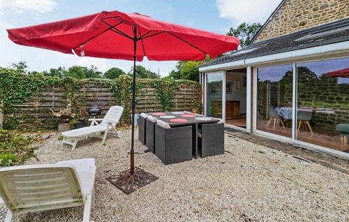 a red umbrella and two chairs and a table at 2 Bedroom Gorgeous Home In Noyal-Sous-Bazouges in Noyal-sous-Bazouges