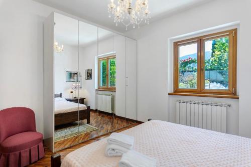a bedroom with two beds and a chair and a mirror at Villa Porlezza Lake view in Cima