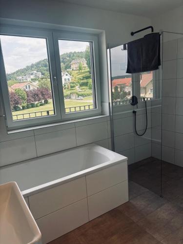 a bathroom with a bath tub and two windows at Penthouse mit Seeblick & Terrasse Top 7 in Reifnitz