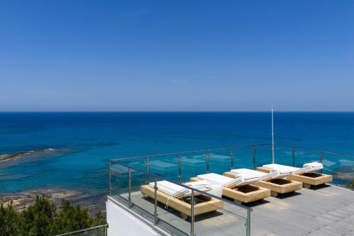 a balcony with lounge chairs and the ocean at Icarus Luxury Beachfront Villa in Gialiskari