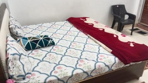 a bed with a red blanket on top of it at Pandeyji stay in Ayodhya