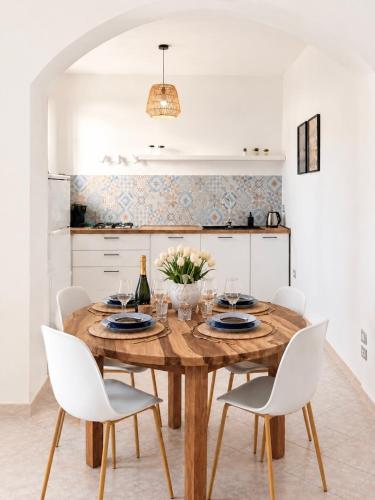 a dining room with a wooden table and white chairs at Alguer Zizì in Alghero
