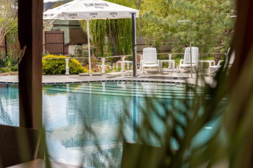 a swimming pool with chairs and an umbrella at Levendula Resort és Rendezvényközpont in Bogács