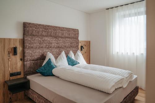 a bedroom with a large white bed with blue pillows at Montoni Chalets in Prato allo Stelvio