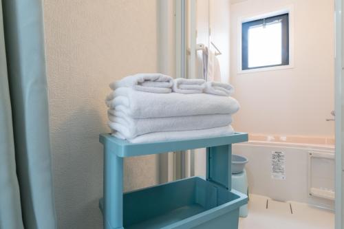a stack of towels on a blue shelf in a bathroom at Mary's Room Hakata in Sumiyoshi