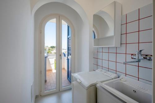 a white bathroom with a sink and a window at Casa del Riccio fronte mare in Mola di Bari
