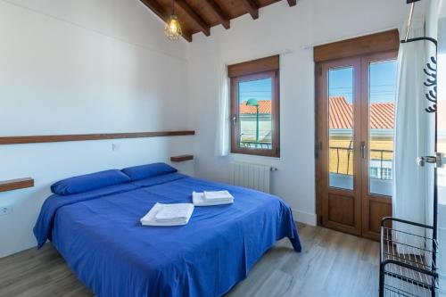 a bedroom with a blue bed and a window at El Rincón de Denver 2 in Suances
