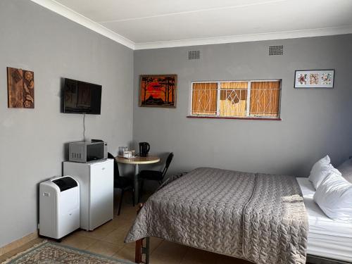 a bedroom with a bed and a table with a tv at Phapel Home-Away in Pretoria