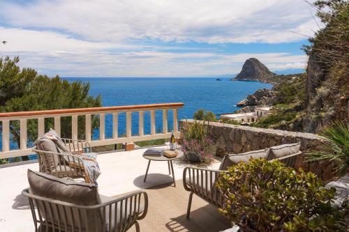 a patio with chairs and a table and the ocean at Seafront Collection - Bungalows and Villas in Aspra