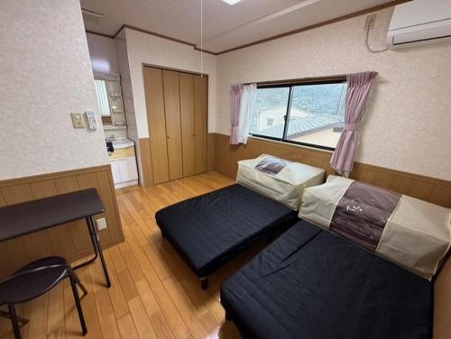 a room with two beds and a desk and a window at GATE80長崎 坂の街長崎 無人宿 完全セルフ 予約メッセージ欄確認要す スマートロック 暗証番号チェックイン 素泊まり専門 アメニティ持参で格安滞在 セコム24h監視 駐車場4台 in Nagasaki