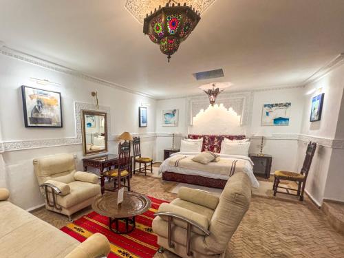 a bedroom with a bed and a couch and chairs at Riad Al-Qurtubi in Tangier