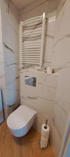 a white toilet in a bathroom with marble walls at Wschód Słońca Ełk in Ełk