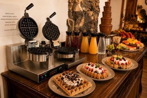 a table with three desserts on plates next to a coffee maker at DWOREK MYŚLIWSKI HUBERT- przy samych Termach Bania i Stoku Narciarskiego Kotelnica, na miejscu wypożyczalnia nart, rowerów elektrycznych w atrakcyjnej cenie dla gości in Białka Tatrzańska