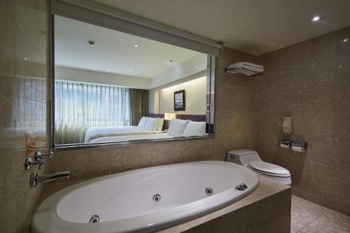 a bathroom with a bath tub and a bedroom at K Hotel - Yunghe in Yonghe