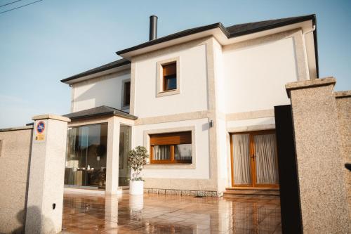 a white house with a black roof at Villa Montalvo Beach-Piscina climatizada in Montalvo