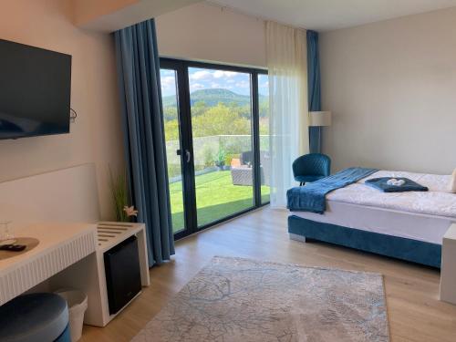 a bedroom with a bed and a sliding glass door at Duna Corner Panzió in Kismaros