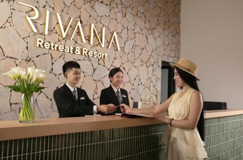 a woman shakes hands with a man at a reception desk at Rivana Retreat in Sóc Sơn