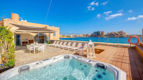a hot tub on a deck with a view of the water at Valletta Waterfront Villa with Pool and Jacuzzi in Valletta