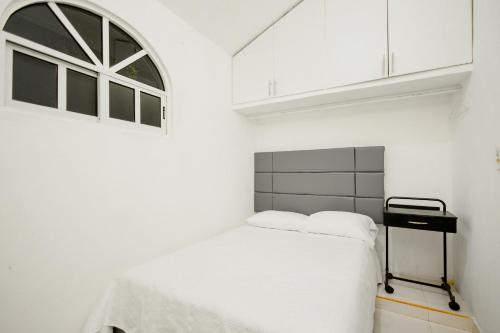 a white bedroom with a bed and a window at Departamento 1 Hab con Alberca, Gym y Terraza in Mérida