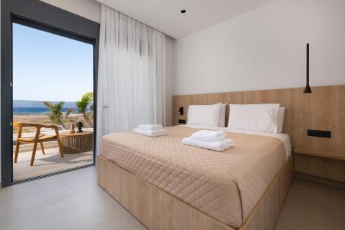 a bedroom with a bed with a view of the ocean at Palmeral Luxury Villas in Kremasti
