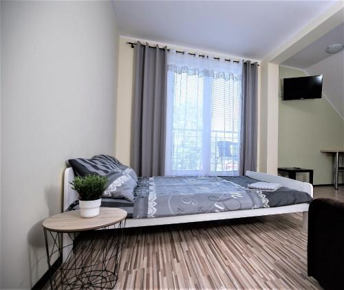 a bedroom with a bed and a table and a window at Aparthouse Kretowiny in Kretowiny
