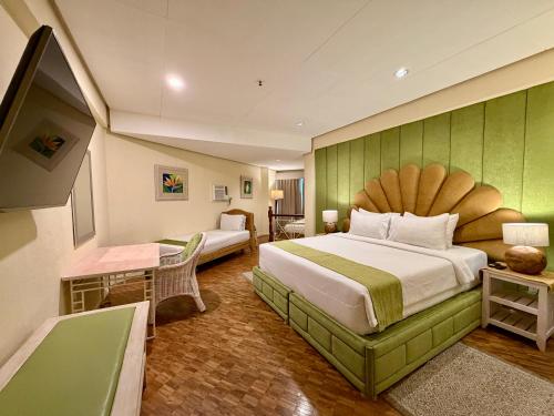 ein Hotelzimmer mit einem großen Bett und einem Schreibtisch in der Unterkunft Coco Grande Hotel in Dumaguete