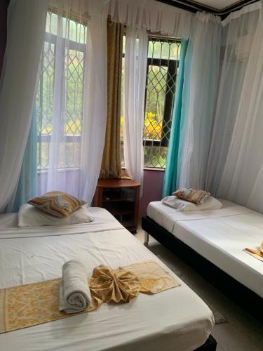 two beds in a room with a window at Amboseli 2 in Mombasa