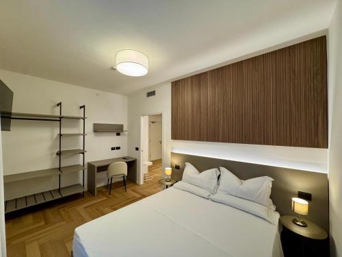a bedroom with a white bed and a desk at Hotel Eden in Bibione