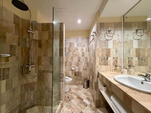 ein Badezimmer mit Dusche, Waschbecken und Toilette in der Unterkunft Coco Grande Hotel in Dumaguete