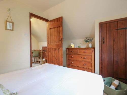 a bedroom with a bed and a wooden dresser at Barclay Cottage in Ashford