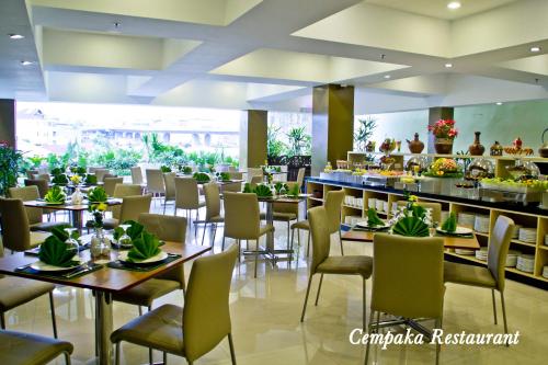 un restaurante con mesas y sillas y un bar en De Batara Hotel, en Bandung