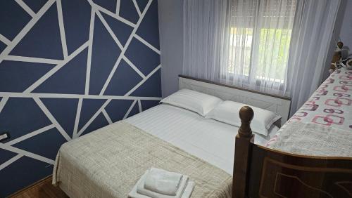 a bedroom with a bed with a blue and white wall at Titi's home Velipoje in Velipojë