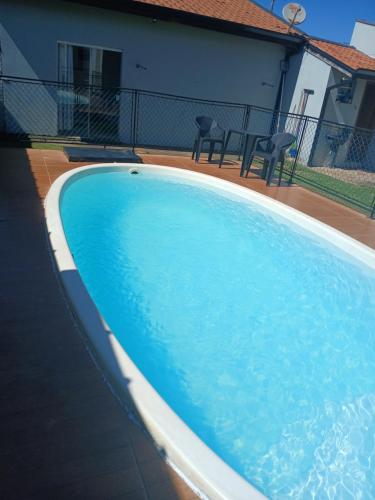 a blue swimming pool with two chairs and a house at Recanto Lyra in Indaiatuba