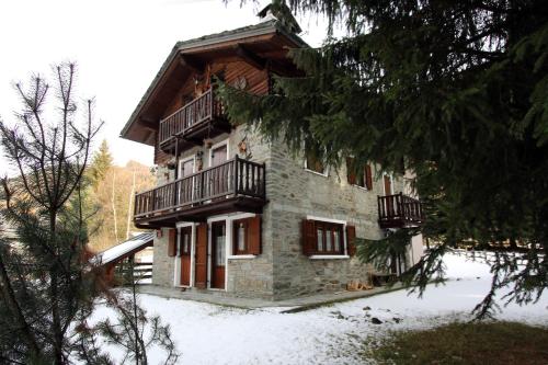 a stone building with balconies and snow on the ground at Champoluc Apartment in Champoluc