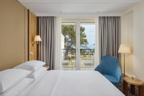a hotel room with a bed and a blue chair at Crowne Plaza Budva by IHG in Budva