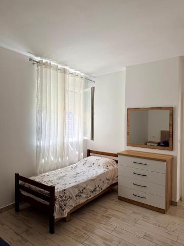 a bedroom with a bed and a dresser and a mirror at Il Sol Apartment in Lezhë