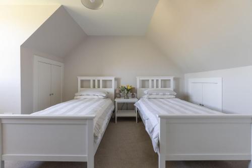 two beds in a bedroom with white walls at Coldwells Farmhouse in Dalkeith